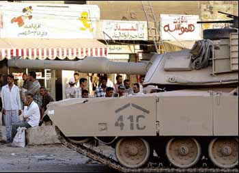 Iraqi's look an US tank rolling through south Baghdad (AFP)