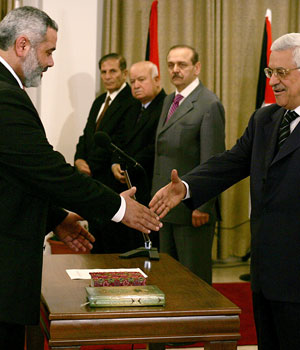 Palestinian Authority President Mahmoud Abbas (R) shakes hands with new Prime Minister Ismail Haniya after he swore in his Hamas government in Gaza City, 29 March 2006 (AFP)