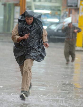 Iraqi man crosses a street under unusually heavy rain that engulfed Baghdad on Sunday (EPA)