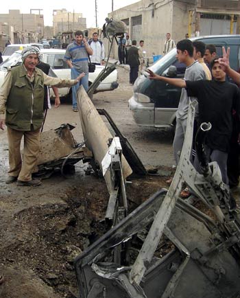 Iraqis flash the "V" sign as they stand near the wreckage of a Humvee in the restive city of Ramadi, west of Baghdad (AFP)