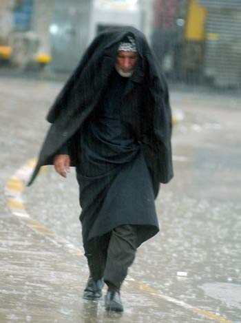 Iraqi man crosses street under unusually heavy rain that engulfed Baghdad on Sunday 02 April 2006 (EPA)