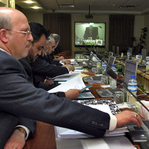 Members of the Palestinain cabinet watch their Prime Minister Ismail Haniyeh on a screen in the West Bank city of Ramallah during the new Hamas-led Palestinian cabinet meeting  held simultaneously in Ramallah and Gaza City, 5 April 2006 (AFP)