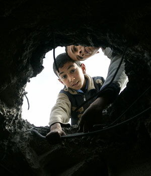 Palestinian boys look through a hole made by an Israeli helicopter after an attack at the Fatah movement office early on Friday in northern Gaza April 7, 2006 (REUTERS)