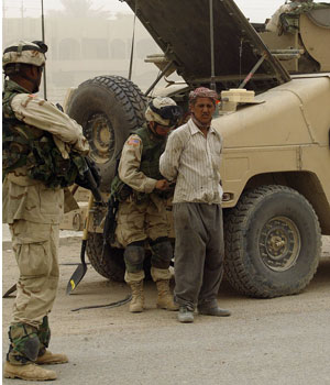 US soldiers arrest a suspected Iraqi construction worker close to the area where a roadside bomb targeted at a US military convoy, killed one US soldier 11 June, 2005 (AFP)
