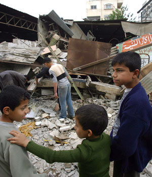 Youngs Palestinians stand in front of a workshop damaged last night by Israeli shelling in Gaza City, 18 April 2006 (AFP)