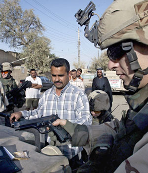 A US soldier of Delta Company inspects a 9mm pistol seized from an Iraqi arrested under suspicion of being part of a rebel group preparing a car bomb attack on the southern outskirts of Baghdad, 8 June, 2005 (AFP)