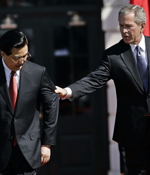 US President George W. Bush (R) assists Chinese President Hu Jintao (L) to his spot during a welcoming ceremony on the South Lawn of the White House in Washington, DC, 20 April 2006 (AP)