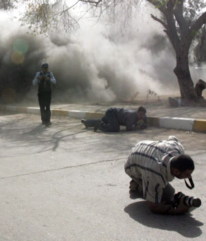 Iraqi photographers and policemen run for cover as a road side bomb explodes in Baghdad's Al-Qadsya district, 21 April 2006 (EPA)