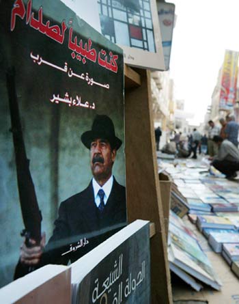 Iraqi men browse a street side booksellers wares, including a book about former Iraqi strongman Saddam Hussein (AP)