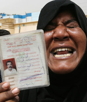 Iraqi woman shows identification card of her late husband she claimed was killed by insurgents, during a protest in Baghdad, May 1, 2006 (REUTERS)
