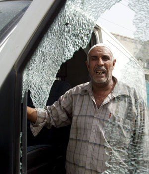 An Iraqi man is seen through the shattered side window of an ambulance car at the site of a roadside bomb explosion in front of the Turkish embassy in Wazrya district in Baghdad, 01 May 2006 (EPA)