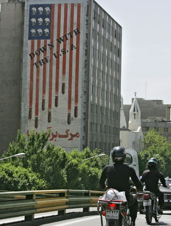 Iranian motorists ride their motorbikes past an anti-US mural in central Tehran (AFP)