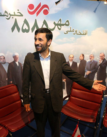 Iranian President Mahmoud Ahmadinejad, gestures, in front of a banner showing Iranian and foreign officials as he visits a press fair (AP)