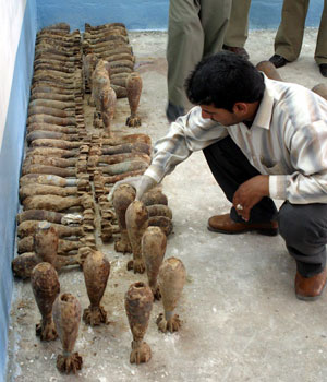 A plainclothes Iraqi policeman inspects mortar rounds inside police headquarters in Najaf, 160 km (100 miles) south of Baghdad, May 9, 2006 (REUTERS)