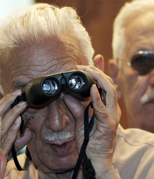 An Iraqi stock market investor uses a pair of binoculars to view trading inside the Iraqi Stock Exchange in Baghdad May 10, 2006 (REUTERS)