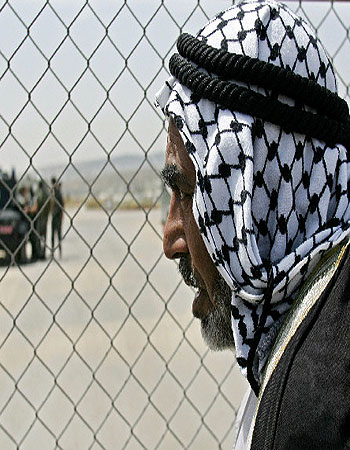 A Palestinian man looks through a fence near the West Bank city of Ramallah (R)
