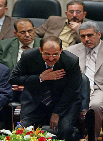 Iraqi Prime Minister Nuri al-Maliki smiles while acknowledging parliamentarians in Baghdad (R)
