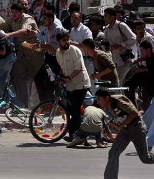 Palestinians run during a shootout between Palestinian police loyal to President Mahmoud Abbas and Hamas gunmen and members of the new security force of the Hamas-led government in Gaza City, May 22, 2006 (AP)