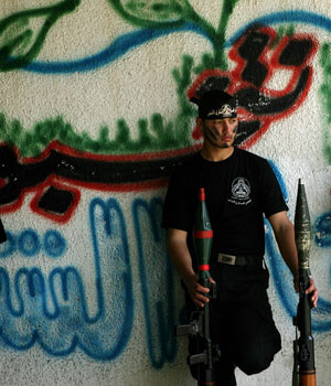 A Palestinian militant from the Fatah movement Al-Aqsa Martyr's Brigade holds weapons during a rally in Gaza City, May 24, 2006 (AP)