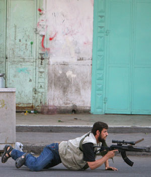 Hamas militia take cover during a gunfight with Palestinian security forces loyal to President Mahmoud Abbas in the Sabra neighborhood, in Gaza City (AP)