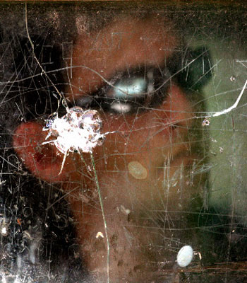 An Israeli soldier watches from behind glass at a military position in the West Bank city of Hebron May 28, 2006 (R)