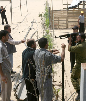 Palestinian policemen argue with a squatter as Palestinian police attempt to destroy illegal buildings in the former Jewish settlements which were evacuated last August under the instruction of the Israeli government, 30 May 2006 (AFP)