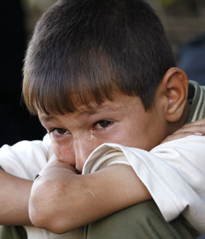An Iraqi boy cries as he waits outside Baghdad's al-Yarmouk hospital June 1, 2006. Two of his brothers were shot by unknown gunmen - killing one and seriously wounding the second (REUTERS)