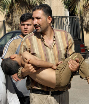 A father carries his injured son to al-Kindi hospital, after two bombs struck in quick succession at a pet market in central Baghdad, killing at least five people and wounding 57 in Iraq, June 2, 2006 (AP)