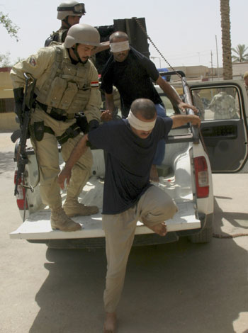 Iraqi soldiers escort suspected insurgents out of the back of a truck after a raid in Latifiya (R)