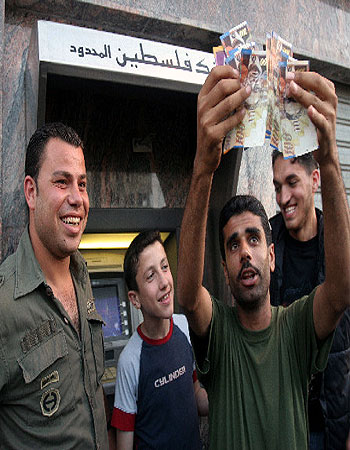 A Palestinian policeman displays money he withdrew a bank machine (AP)