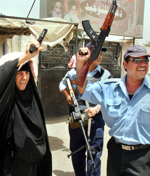 Iraqi police officers and an elderly woman fire guns in the air to celebrate the news that Abu Musab al-Zarqawi, al-Qaeda's leader in Iraq has been killed in an air raid north of Baghdad, (AP)