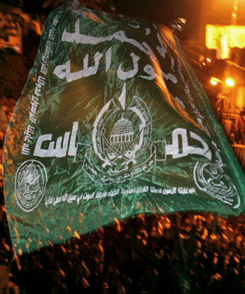 A Palestinian Hamas supporter waves a green Islamic flag as thousands of Palestinians attend a demonstration at the Palestinian Parliament in Gaza City (AP)