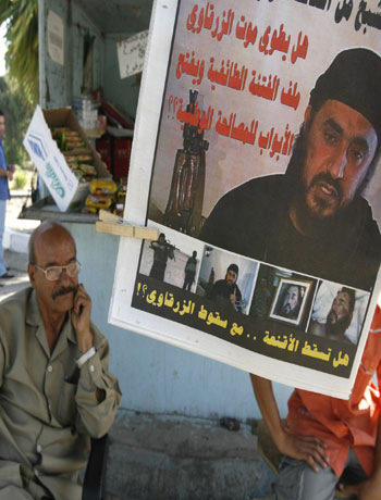 Newspaper vendor displays poster of Abu Musab al-Zarqawi in Baghdad (R)