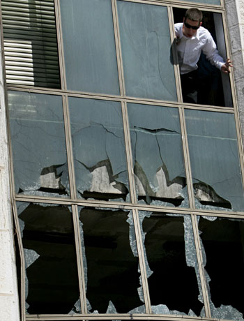 Palestinian man stands above shattered window of Palestinian parliament in Ramallah (R)