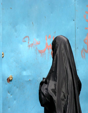 An Iraqi woman waits at the gate of a morgue of a local hospital to receive the body of her son who was killed in a car bomb explosion (EPA)
