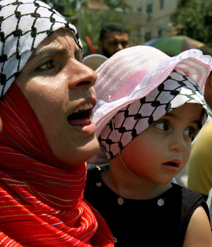 Palestinian government employees who have not been paid since March shout slogans, along with a young child, during a protest outside of the parliament house in Gaza city, June 19, 2006 (AP)