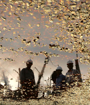 Palestinian workers are seen from a reflection from a puddle at the headquarters of a power company destroyed by Israeli airstrikes in central Gaza Strip June 28, 2006 (REUTERS)