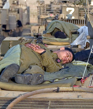 Israeli soldiers sleep on top of their tanks in Meflasim near the northern border of the Gaza strip, 29 June 2006 (EPA)
