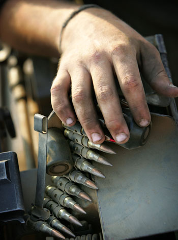 The hand of an Israeli soldier leans on a magazine of bullets as troops prepare to enter the Gaza Strip (AP)
