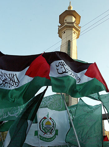 Palestinian and Hamas flags aloft during a demonstration of some 2000 Palestinians who rallied in Yarmouk refugee camp,southern Damascus (AP)