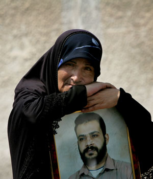 A Palestinian woman holds a portrait of her son, held prisoner in an Israeli jail, during a demonstration to demand the release of prisoners outside the Egyptian embassy in Gaza City, July 3 2006 (AP)