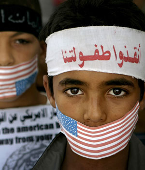 Palestinian boys with their mouths covered with the US flag, attend a demonstration to demand the US to pressure Israel to stop the ongoing military campaign in the Gaza Strip, Rafah, July 5, 2006 (AP)