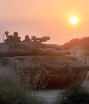 An Israeli tank advances towards the northern Gaza Strip at sunrise from a military staging area near Kibbutz Zikim in southern Israel, early Thursday July 6, 2006 (AP)