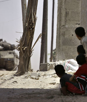 Palestinian children take cover as they watch an Israeli tank advance during a military operation in Beit Lahiya, northern Gaza Strip, July 6, 2006 (AP)