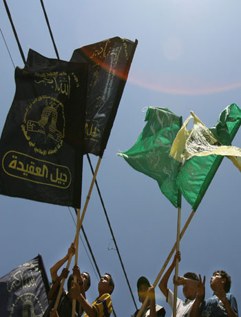 Palestinian boys hold up flags from the Hamas, Fatah and Islamic Jihad movements during a funeral in Gaza (AFP)