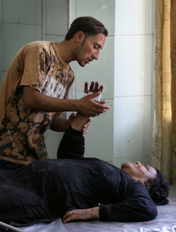 A young Iraqi man comforts his mother who suffered wounds in crossfire during street fights in the Jihad area of western Baghdad, Iraq (AP)