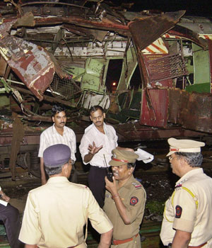 Police investigate near a train destroyed by a bomb blast at Mahim railway station in Bombay, India, July 11, 2006 (AP)