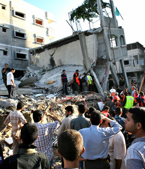 Palestinians check and search for survivors in a three-storey building that was brought down by an Israeli strike in Gaza City, July 12, 2006 (REUTERS)