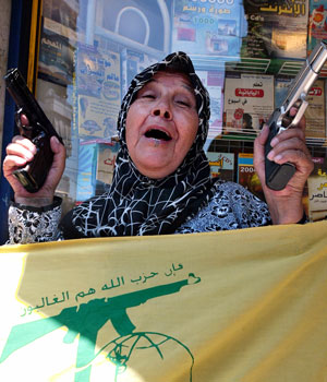A Lebanese woman, brandishing guns, jubilates in Beirut's southern suburbs after pro-Iranian Hezbollah fighters captured two Israeli soldiers in south Lebanon, 12 July 2006 (AFP)