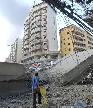 A man holding the Hezbollah flag inspects a bridge that was knocked down when Israeli air raids targeted it, in the suburbs of Beirut, Lebanon, July 14, 2006 (AP)